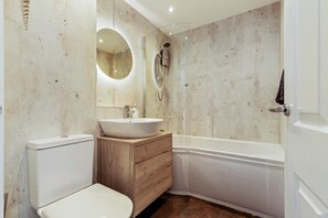 A bathroom with a toilet, sink, vanity, and bathtub. - 25 Coedrath Park - Sea Views From Balcony Short Walk to Beach Parking (Saundersfoot)