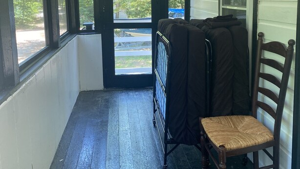 A narrow corridor with a wooden floor, a chair, and a cart. - Newfound Lake Cozy Cottage (Bristol)