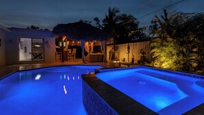 Una piscina con una estructura de techo de paja y una valla de madera.