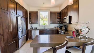 Una cocina moderna con armarios de madera oscura, electrodomésticos de acero inoxidable y una isla central con sillas.