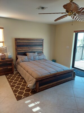 A bedroom with a bed, wooden headboard, nightstand, lamp, and a ceiling fan.