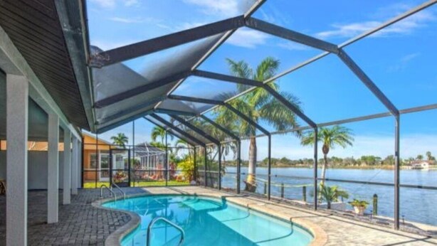 Piscina interna com vista para um lago, cercada por um terraço coberto com palmeiras.