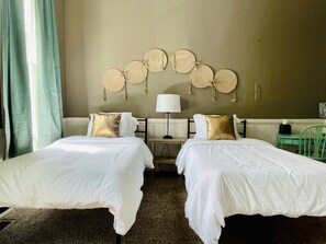 A hotel room with two beds, a lamp, and a wall decorated with circular wall hangings. - Leaning House of Haynie | Trendy 2BR/1BA Apartment (Evansville)