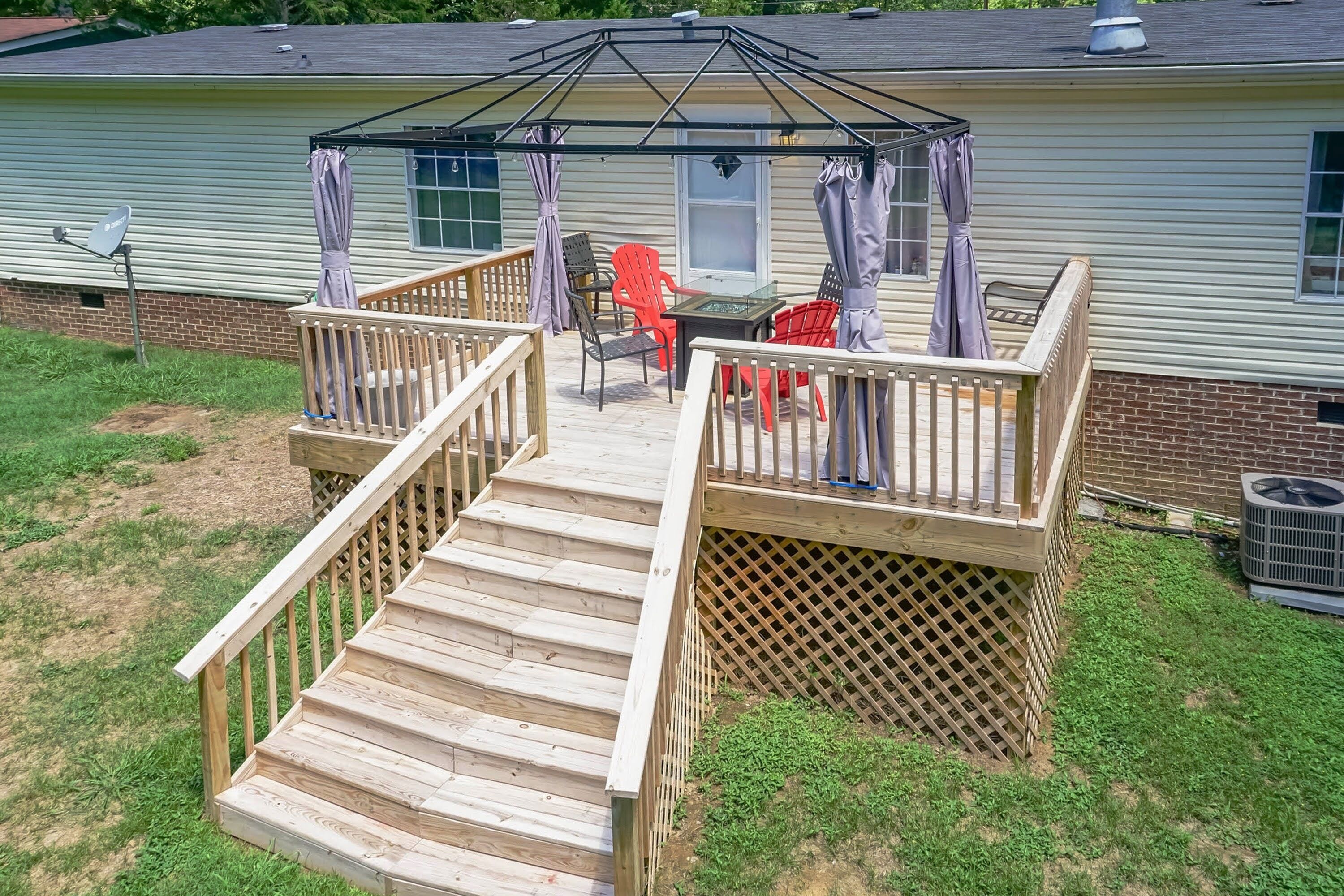 Una terraza con una pérgola, mobiliario exterior y una casa de ladrillo al fondo.