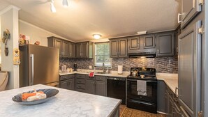 A modern kitchen with dark cabinets, a stainless steel refrigerator, and a tiled backsplash. - Discover Durham, just a quick 11-minutes from Duke University (Durham)