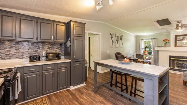A modern kitchen with dark cabinets, a microwave, and a large island with stools. - Discover Durham, just a quick 11-minutes from Duke University (Durham)