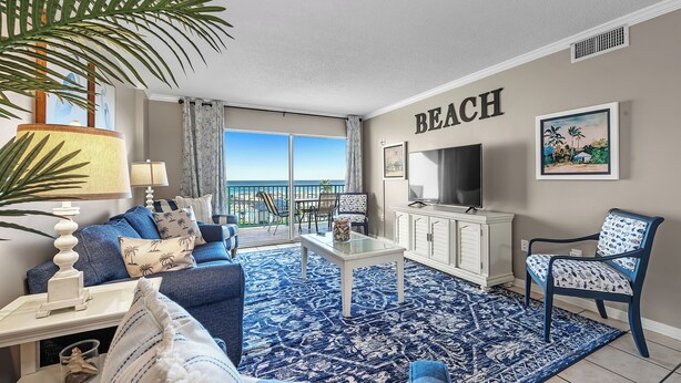 A living room with a view of the beach, a sofa, a coffee table, a TV, and a chair. - Gulf Shores Plantation-Palms 6402 (Gulf Shores)