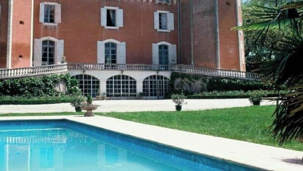 Un grande edificio storico con piscina antistante, immerso nel verde.