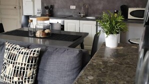 Una cucina moderna con mobili bianchi, un piano di lavoro grigio e un piano cottura integrato.