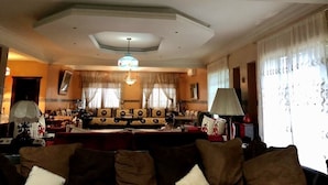 Ein gemütliches Wohnzimmer mit einer Sofagarnitur, einem Chandelier und einem großen Fenster mit Vorhängen.