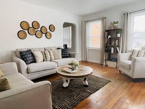 Una sala de estar con un sofá, sillones, una mesa de centro y una estantería.