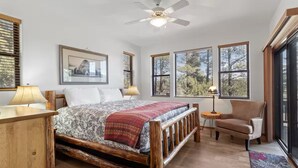 A bedroom with a wooden bed, a chair, a small table, and large windows. - 5 🌟 Luxury Torreon  (Show Low)