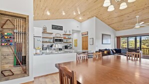 A spacious kitchen with a wooden ceiling, a dining area with a large table and chairs, and a view of the outdoors through large windows. - 5 🌟 Luxury Torreon  (Show Low)