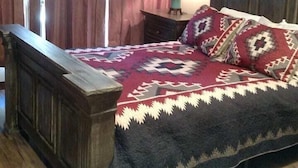 Une chambre à coucher avec un lit en bois, une table de chevet, une lampe et une fenêtre avec des rideaux.