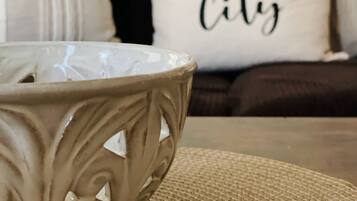 Un bol posé sur un set de table en fibres tressées, un canapé avec un coussin orné de l’inscription « River City », et un mur d’où l’on aperçoit une partie d’une fenêtre.