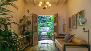 A cozy room with a bed, a desk, and a view of a lush garden. - Hotel Quinta Ladera (Medellín)
