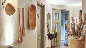 A hallway with wooden flooring, a door with a number, and various wooden utensils and baskets on the wall. - Hotel Quinta Ladera (Medellín)