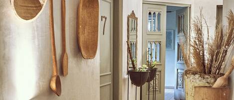 A hallway with wooden flooring, a door with a number, and various wooden utensils and baskets on the wall.