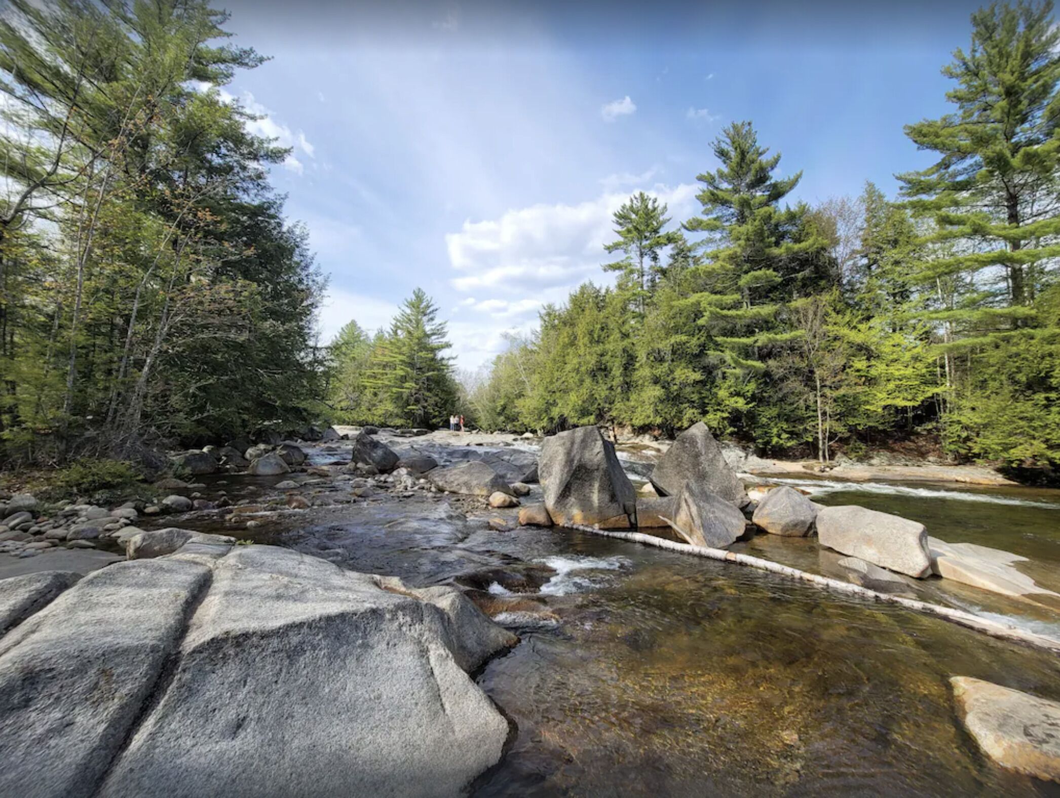 Un paisaje natural con un río, rocas y árboles.