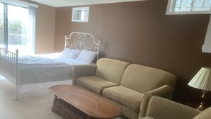 Een slaapkamer met een bed, een bank, een salontafel en een lamp.