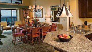 Une cuisine moderne avec des comptoirs en granit, un coin repas avec des chaises en bois et une grande fenêtre donnant sur l’océan.