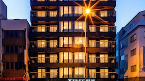 A multi-story hotel with balconies, a well-lit entrance, and a clear sky. - WELLSTAY Shinsekai Wakyo (Osaka)