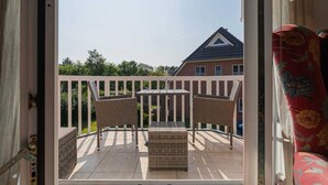 A balcony with wicker furniture and a view of a brick building. - Apartment 4 Müller (ID 425) (Sankt Peter-Ording)