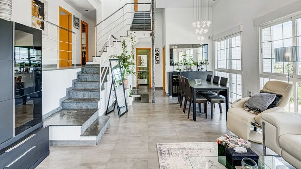 Un interior moderno con una escalera que conduce a un comedor, una cocina y una sala de estar con un sofá y una mesa de centro.