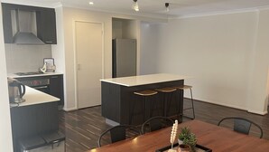 Une cuisine moderne avec des meubles de couleur sombre, un plan de travail blanc et un four encastré.