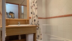 Ein Badezimmer mit Holzwaschtisch, Spiegel, Waschbecken, Toilette und Badewanne.