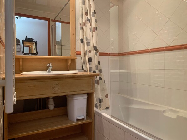 Un baño con tocador de madera, un espejo, un lavabo, un inodoro y una bañera.