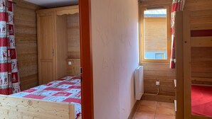 Ein kleines Zimmer aus Holz mit einem Bett, einem Fenster und einer Heizung.