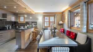 A modern kitchen with wooden accents, a central island, bar stools, and a dining table with a bench.