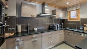 A modern kitchen with stainless steel appliances, grey cabinets, and a wooden ceiling.