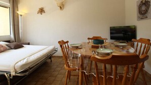 Ein Zimmer mit einem Bett, einem Esstisch mit Stühlen, einem Fernseher und einem an der Wand befestigten Hirsch-Dekoration.