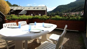Eine Terrasse im Freien mit einem runden Esstisch und weißen Stühlen.
