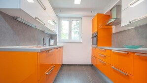 A narrow kitchen with orange cabinetry and a window above the sink. - 3 bedroom cozy apartment in Koper (Koper)