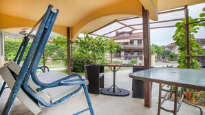 An outdoor patio area with a table and chairs, a pergola structure, and a view of a residential building. - 3 bedroom cozy apartment in Koper (Koper)
