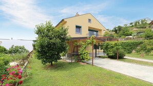 A two-story house with a covered porch and a small garden with flowers. - 3 bedroom cozy apartment in Koper (Koper)