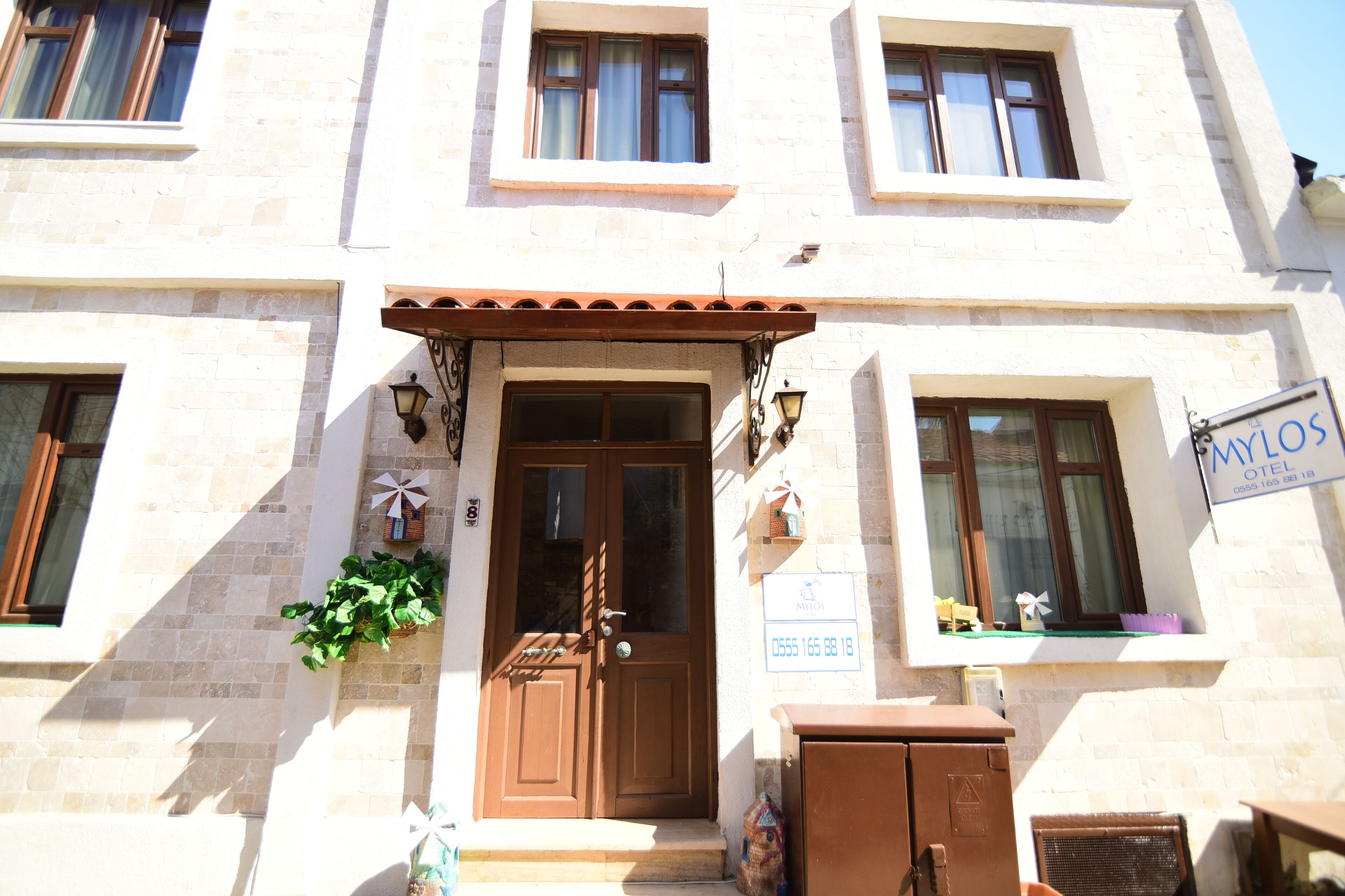 A building with a brown door, windows, and a sign that reads "Milos Hotel."