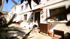 A traditional stone building with a tiled courtyard, a wooden door, and a small porch area. - Mylos Otel (Bozcaada)