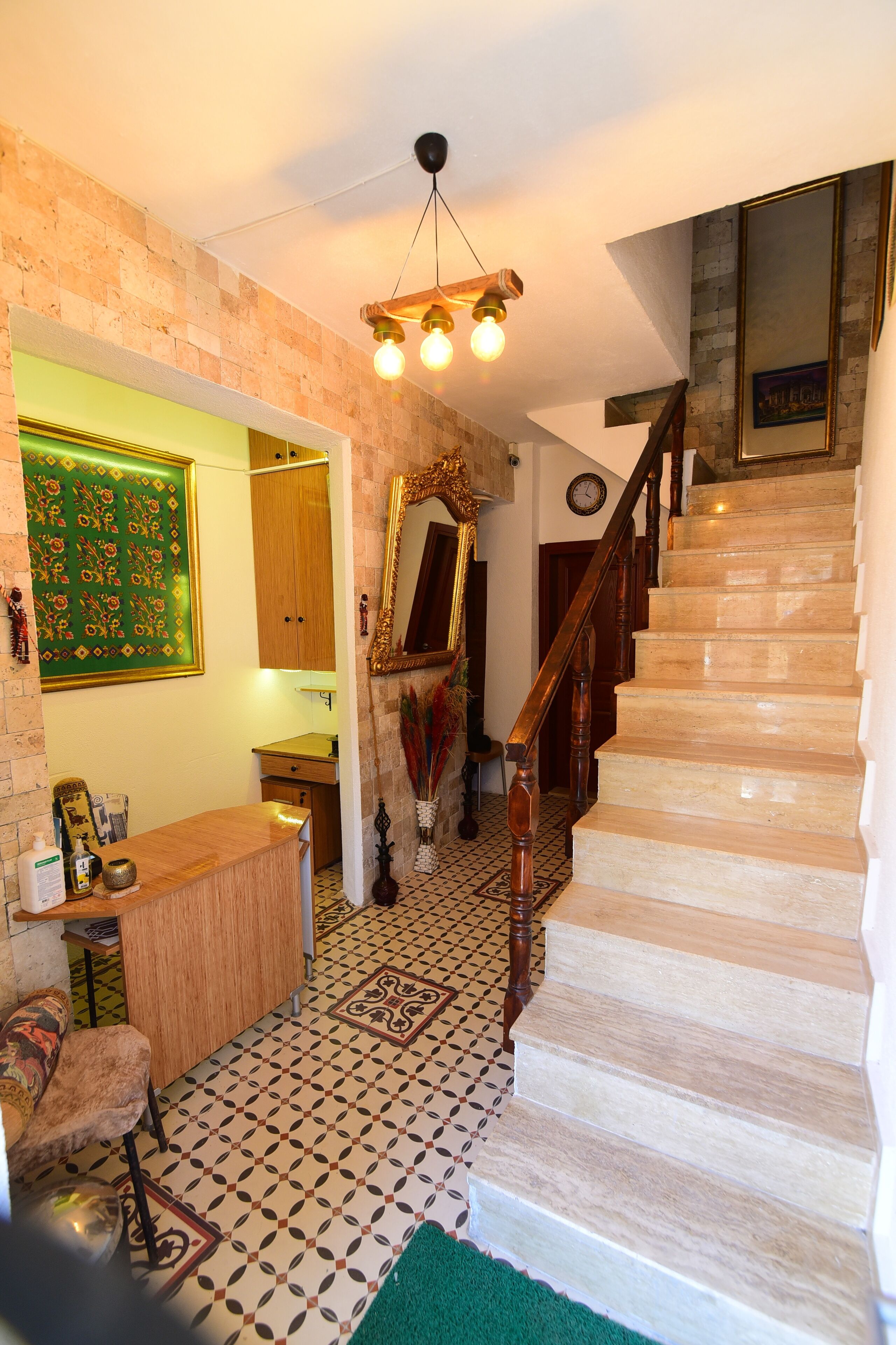 Un escalier avec une rampe en bois, un sol à motifs et un tapis vert.