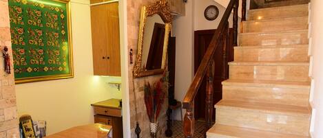 A staircase with a wooden handrail, a patterned floor, and a green rug.