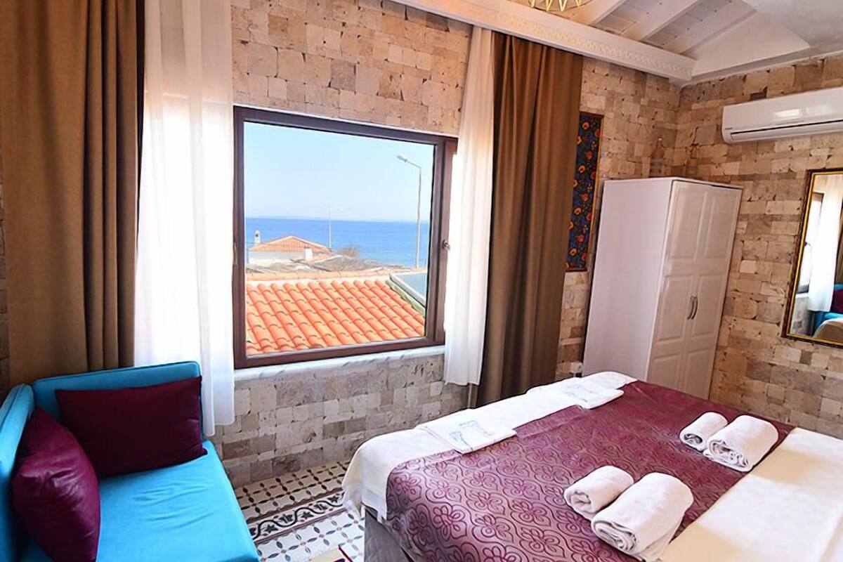 Una habitación de hotel con un ventanal grande, una cama con toallas, un armario y un sofá azul.