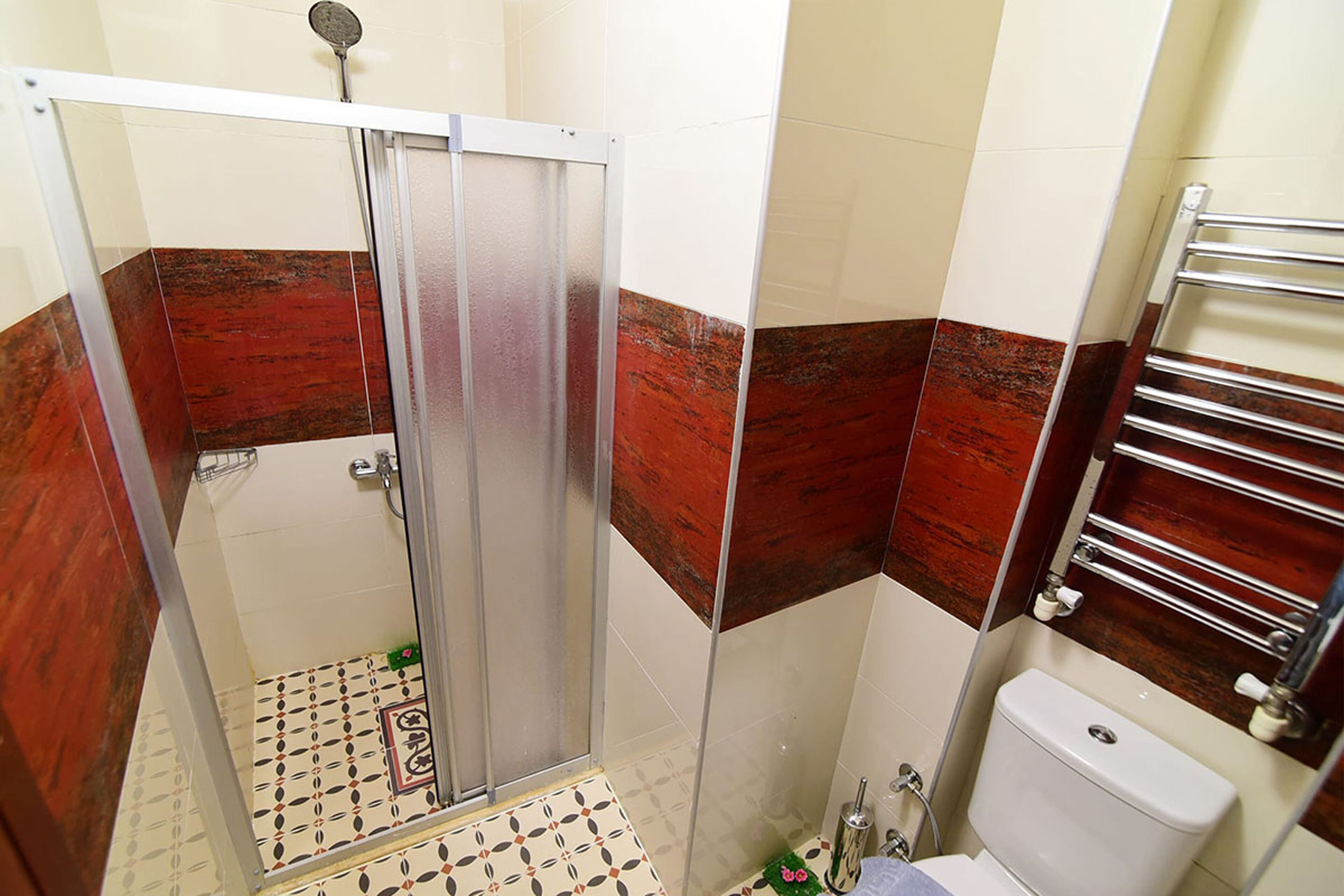 Un baño con cabina de ducha, inodoro y perchero para toallas.