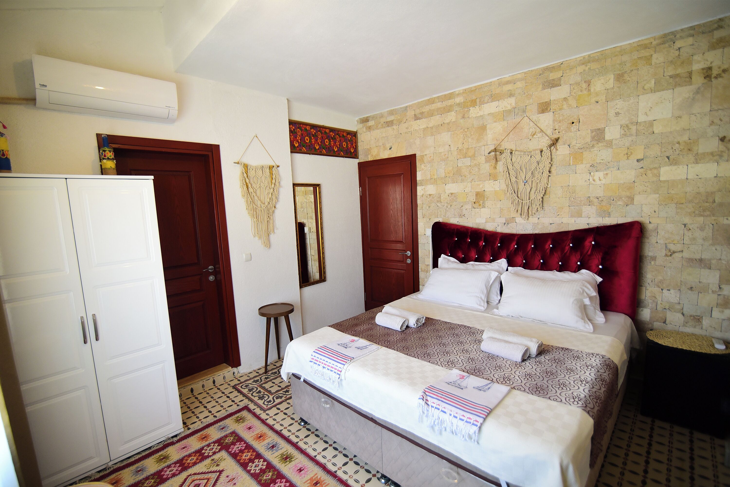 A bedroom with a bed, wardrobe, and a wall-mounted air conditioner.