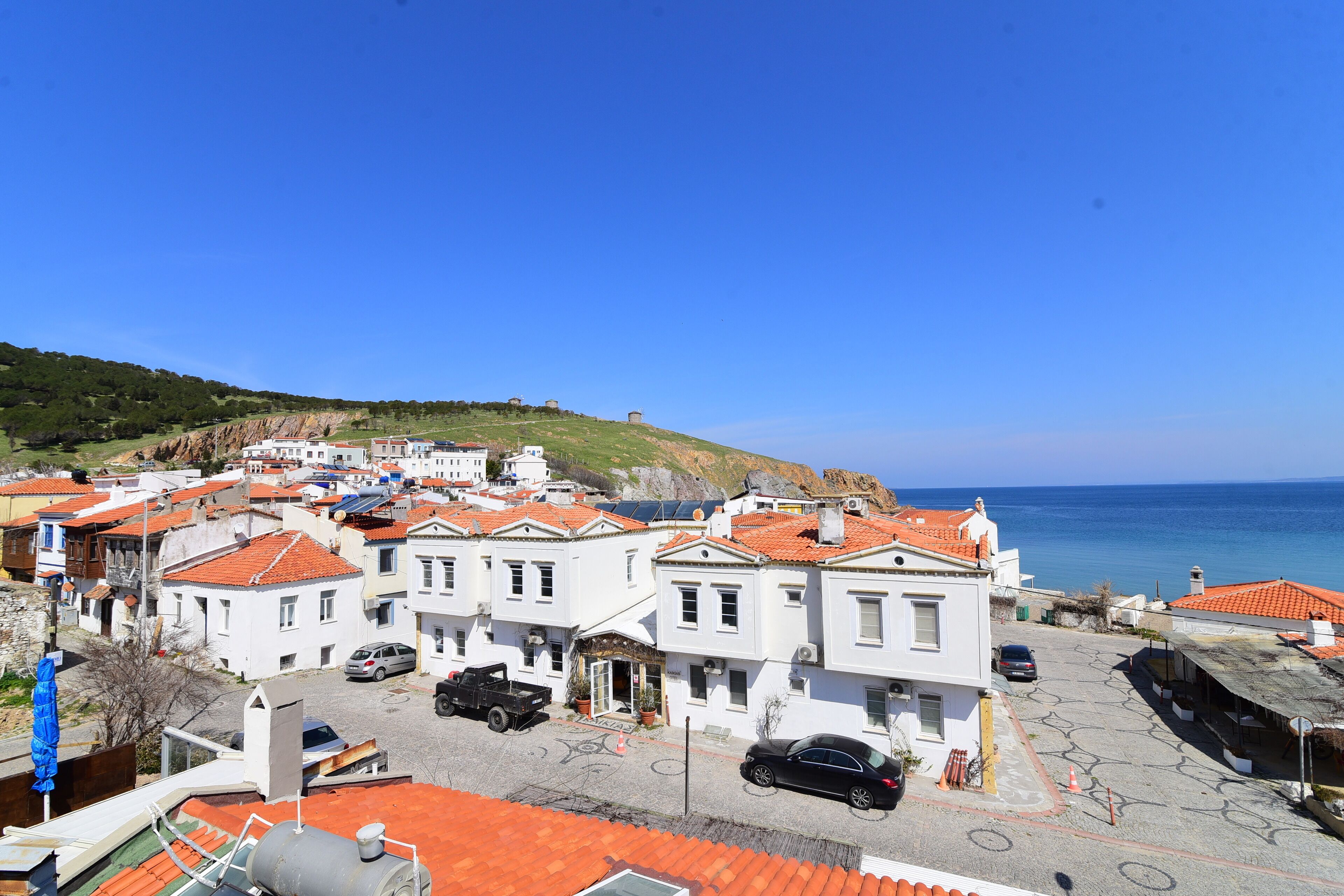 Un pueblo costero con edificios blancos, techos rojos y un cielo azul despejado.