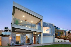 A modern two-story house with a balcony, large windows, and a garage. - Vue Sur La Mer by Ready Set Stay - View of the sea (Mount Martha)
