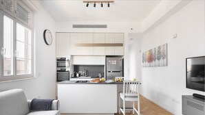 A modern kitchen with a central island, a dining area with a white table and chairs, and a living area with a sofa and a TV. - An amazing gem in the heart of TelAviv (Tel Aviv)