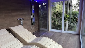 A spa room with wooden loungers, a glass door leading outside, and a shower area with a control panel. - Villa Vittoria Vieste | Private residence with pool (Defensola)